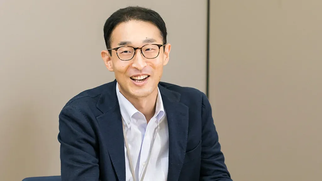 A smiling male Honda employee wearing glasses and a navy blazer.